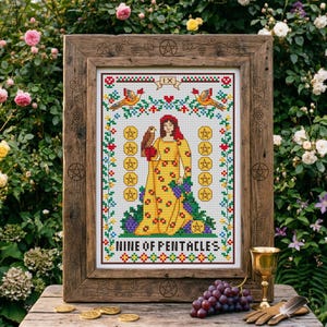 May include: A framed cross-stitch of the Nine of Pentacles tarot card. The artwork features a woman in a yellow dress with a falcon, surrounded by gold coins and floral elements. The wooden frame has decorative carvings.