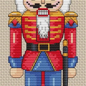 May include: A cross-stitch design of a traditional nutcracker soldier. The figure wears a black hat, red jacket, blue pants, and black boots. The design includes gold, white, and black accents, and a black sword. The background is a neutral beige.
