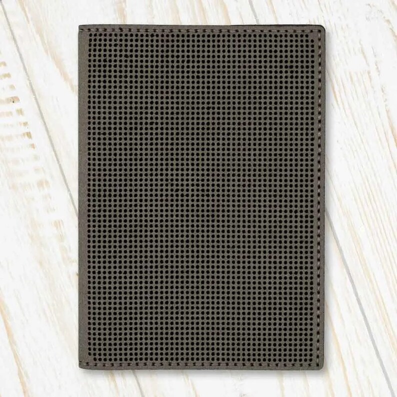 May include: A dark grey passport holder with a textured, grid-like pattern.