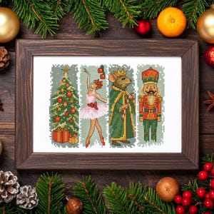 May include: A framed cross-stitch artwork depicting a Christmas tree, a ballerina, a mouse king, and a nutcracker. The artwork is in a dark wooden frame, surrounded by festive decorations, including pine, baubles, and fruit.