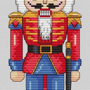May include: A cross-stitch design of a traditional nutcracker soldier. The figure is dressed in a red jacket with gold accents, blue pants, and a black hat. It holds a black sword and has a white beard and mustache.