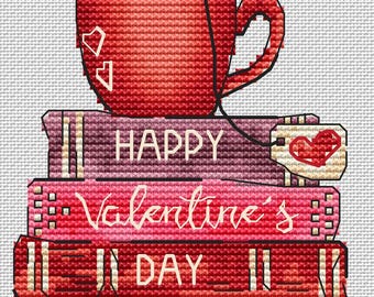 May include: A stack of three red books with the words "Happy Valentine's Day" on the front. A red mug with a heart design sits on top of the books.