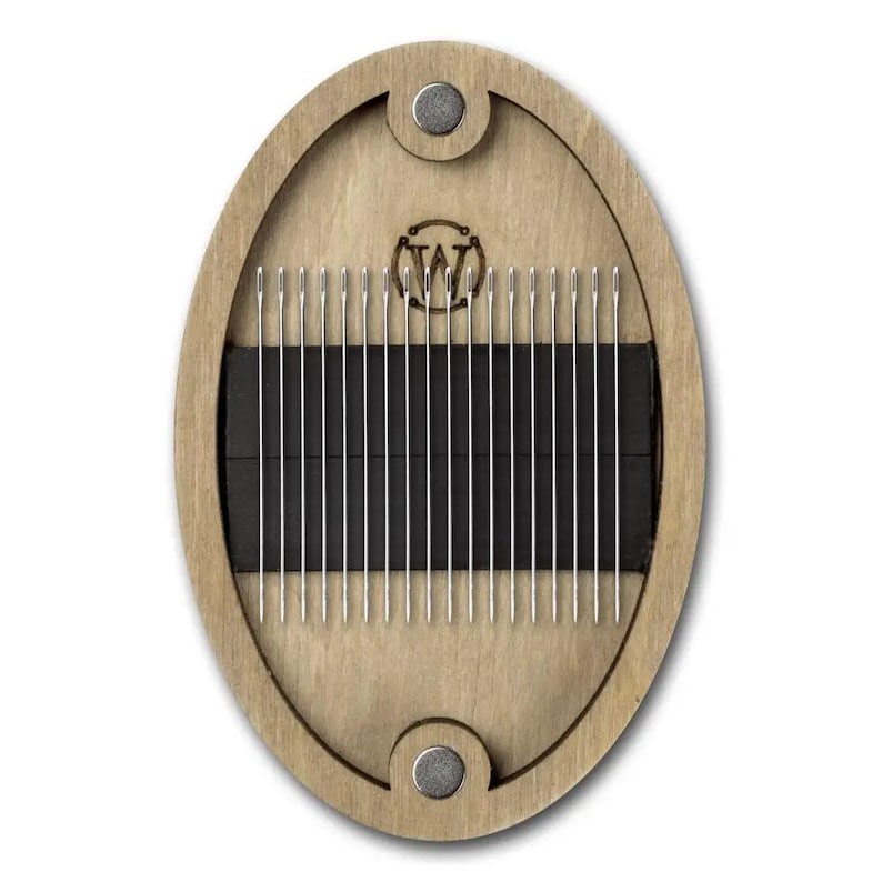 May include: A wooden oval-shaped case with a magnetic closure, containing a set of 24 silver needles. The case has a black interior and a woodgrain finish. The case has a logo of a stylized "W" in the center.