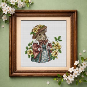 May include: Cross-stitch artwork of a mouse wearing a hat adorned with yellow flowers and a dress. The mouse is surrounded by yellow flowers and framed in a wooden frame. The artwork has a vintage, whimsical feel.