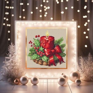 May include: A cross-stitch Christmas design featuring a red candle with a lit yellow flame, surrounded by holly, berries, and a red bow. The artwork is framed in gold and set against a neutral background, evoking a festive holiday theme.