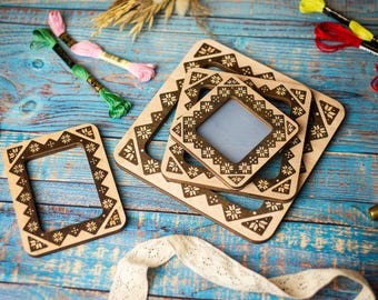 May include: Four wooden picture frames with intricate geometric designs, nested inside each other. The frames are made of light brown wood with dark brown accents. The frames are on a blue wooden surface.