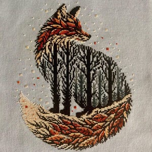May include: Cross-stitch embroidery of a fox with a forest scene inside its body. The fox's tail is curled around the forest scene, and the background is a light blue color.