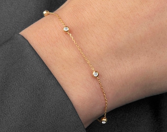May include: A delicate gold chain bracelet with small, clear gemstones. The bracelet is on a person's wrist.