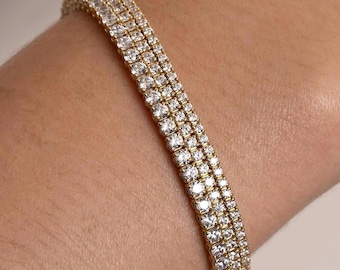 May include: A gold tennis bracelet with a triple row of sparkling diamonds.