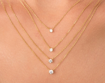Puede incluir: Cuatro cadenas de oro con pequeños colgantes de diamantes superpuestos en el cuello de una persona.