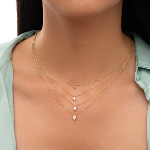 May include: A layered gold necklace with four oval-shaped pendants, each with a small diamond in the centre.