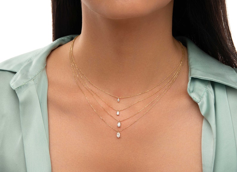 May include: A layered gold necklace with four oval-shaped pendants, each with a small diamond in the centre.