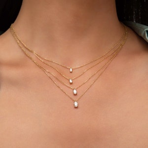May include: A layered gold necklace with four oval-shaped diamond pendants of varying sizes.