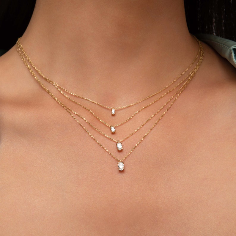 May include: A layered gold necklace with four oval-shaped diamond pendants of varying sizes.