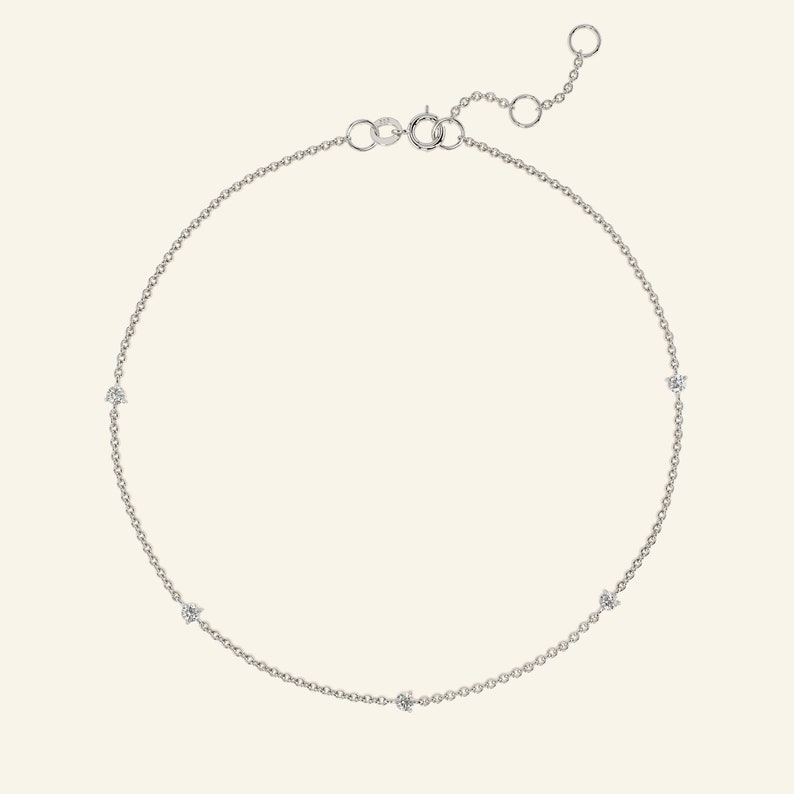 May include: A delicate silver chain anklet with five small, clear gemstones.