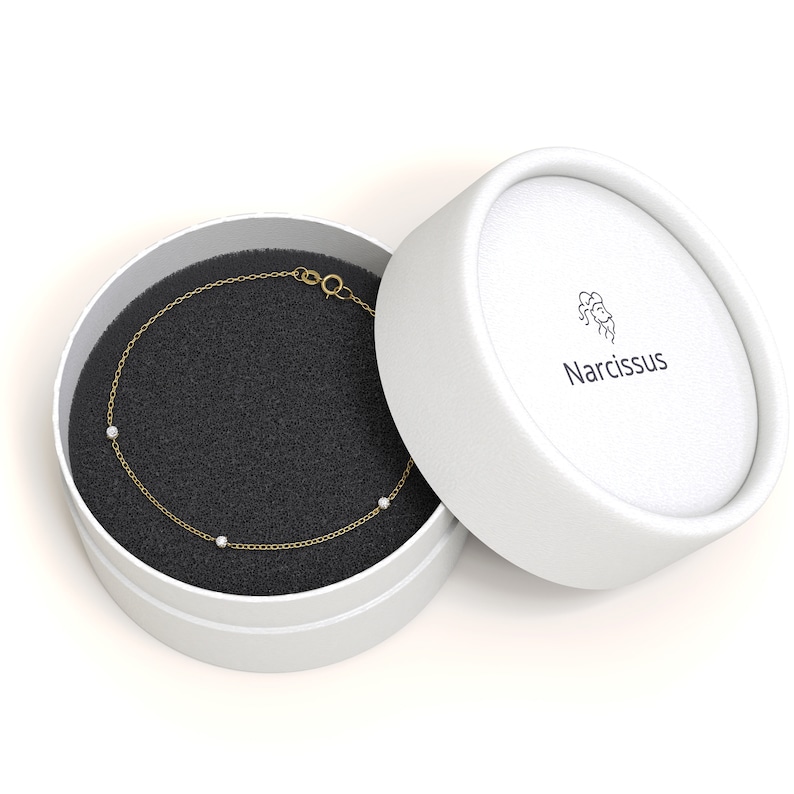 May include: A delicate gold chain bracelet with three small white stones, presented in a white box with the brand name "Narcissus" printed on the lid.