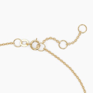 May include: Gold chain necklace with a lobster clasp and an adjustable length. The chain is made of small, round links.