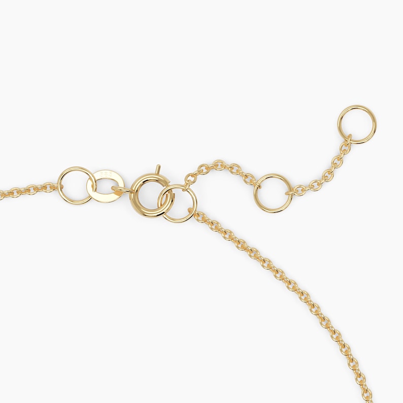 May include: Gold chain necklace with a lobster clasp and an adjustable length. The chain is made of small, round links.