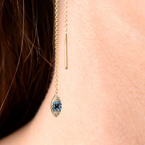 May include: Gold chain earring with a blue evil eye charm. The charm is made of small blue and clear stones.