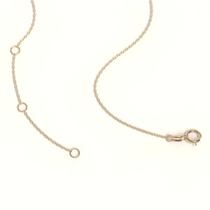 May include: A gold chain necklace with three adjustable loops. The chain has a lobster clasp closure.