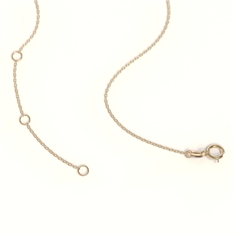 May include: A gold chain necklace with three adjustable loops. The chain has a lobster clasp closure.