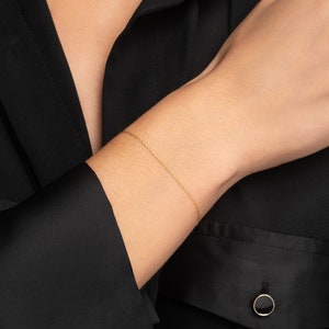 May include: A delicate gold chain bracelet on a person's wrist.
