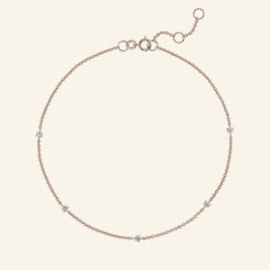May include: A delicate rose gold chain anklet with five small sparkling diamonds.