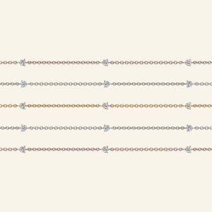 May include: Five delicate necklaces with a simple chain design and two small diamond accents. The necklaces are shown in rose gold, silver, and gold.