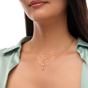 May include: A woman wearing a light green shirt with four gold necklaces with small diamond pendants.