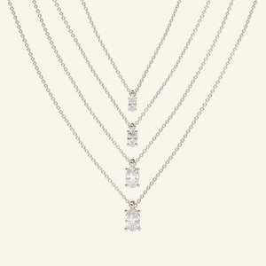 May include: Four silver necklaces with oval-shaped diamond pendants of varying sizes.