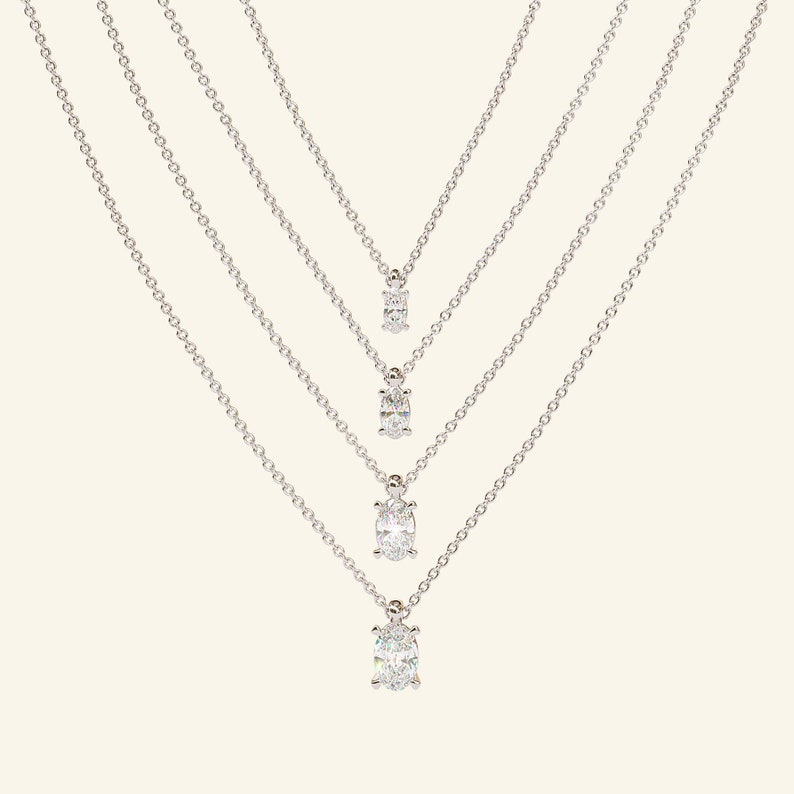 May include: Four silver necklaces with oval-shaped diamond pendants of varying sizes.