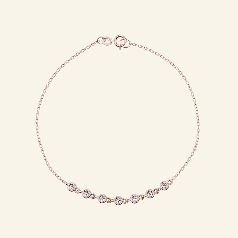 Pu&ograve; includere: Bracciale in oro rosa con una catena sottile e una serie di pietre preziose rotonde e trasparenti. Le pietre sono distanziate lungo il bracciale, creando una sottile lucentezza. Chiusura semplice.