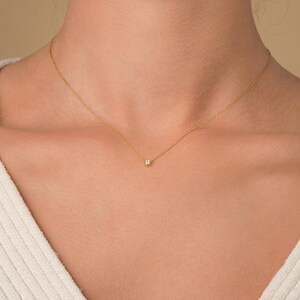 May include: A delicate gold chain necklace with a small, clear gemstone pendant.