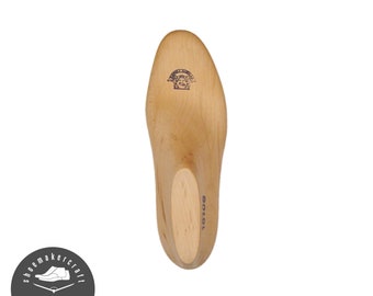 Könnte beinhalten: Ein hellbrauner Holzschuhleisten mit runder Spitze und Ferse. Der Leisten hat einen Stempel in der Nähe der Ferse und die Nummer "10100" auf der Seite. Das Logo des Schuhmachers befindet sich in der linken unteren Ecke.