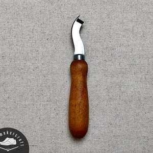 May include: A curved leatherworking knife with a wooden handle. The blade is silver and curved, with a sharp edge. The handle is a warm brown color. The knife is designed for precision cutting in leathercraft projects.