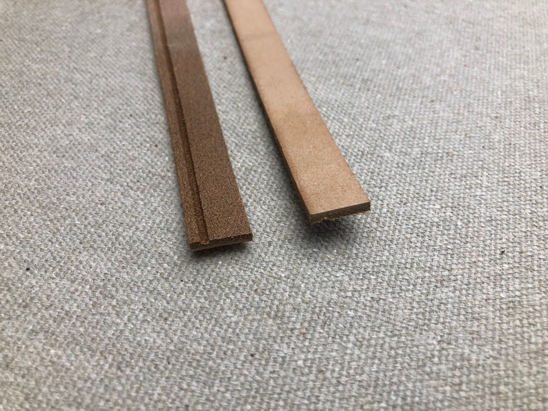 K&ouml;nnte beinhalten: Zwei Streifen braunes Leder werden vor einem neutralen Hintergrund gezeigt. Ein Streifen ist ein dunkleres, strukturiertes Braun, w&auml;hrend der andere ein helleres, glattes Tan ist. Die Streifen sind rechteckig und scheinen f&uuml;r Bastelarbeiten oder Lederarbeiten bestimmt zu sein.