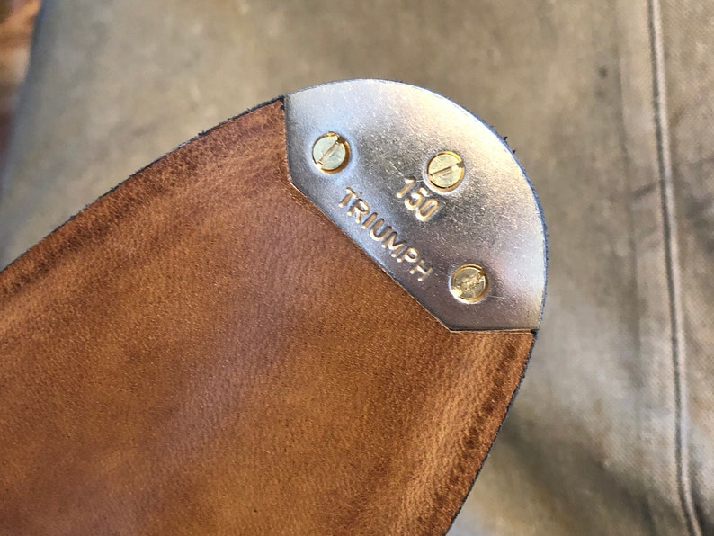 Puede incluir: Primer plano de una suela de zapato de claqu&eacute; de cuero marr&oacute;n con una puntera de metal plateado. La puntera est&aacute; asegurada con tornillos de lat&oacute;n y presenta la palabra "TRIUMPH" y el n&uacute;mero "150".