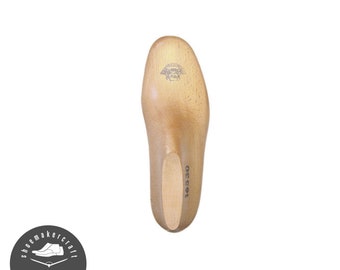 May include: A wooden shoe last, light brown in color, with a rounded toe and heel. The last has a stamped logo and the number "16530" printed on the side. The object is used in shoemaking.