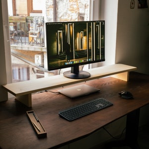 May include: A wooden desk with a black computer monitor, a laptop, a keyboard, a mouse, and a pencil holder. The monitor is on a wooden stand and the desk is made of dark wood.