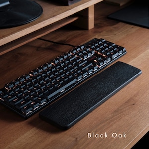 Peut inclure: Un clavier noir avec un repose-poignets en bois noir. Le repose-poignets est étiqueté "Black Oak".