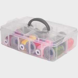 May include: A clear plastic sewing box with a gray handle, filled with colorful spools of thread. The box is divided into compartments, and the thread colors include red, pink, yellow, and green. The box is designed for organizing sewing supplies.