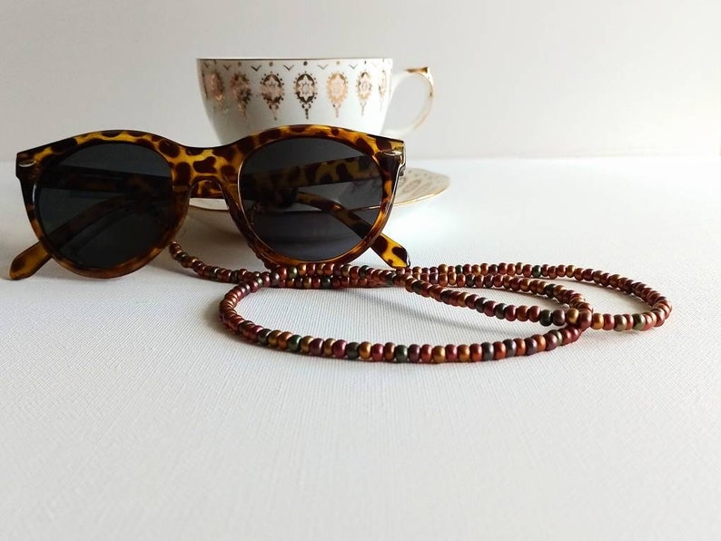 May include: Tortoise shell sunglasses with brown, red, and green beaded eyeglass chain.