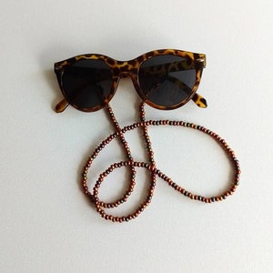 May include: Tortoise shell sunglasses with brown and green beaded chain.