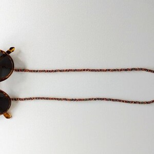 May include: Tortoise shell sunglasses with brown wooden bead chain.