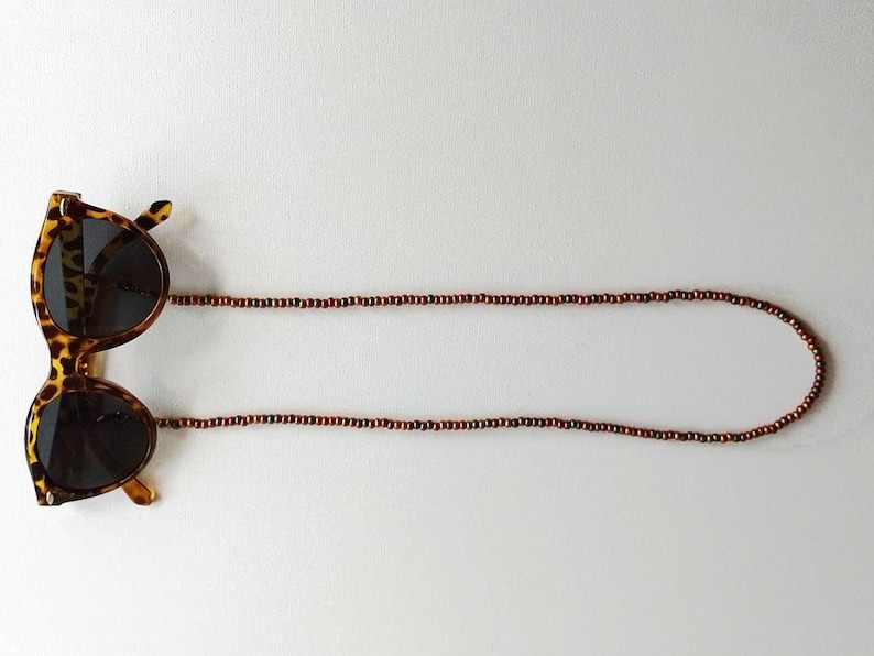 May include: Tortoise shell sunglasses with brown wooden bead chain.