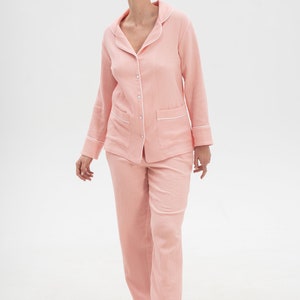 Peut inclure: Un ensemble pyjama rose &agrave; manches longues avec des bordures blanches. Le haut a un devant boutonn&eacute; et un col. Le pantalon a une jambe droite.