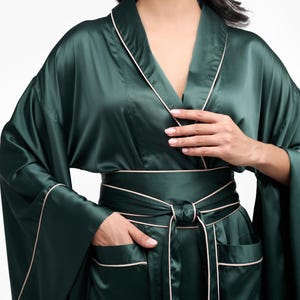 May include: A dark green satin robe with a white trim and a matching sash. The robe has long sleeves and two pockets.