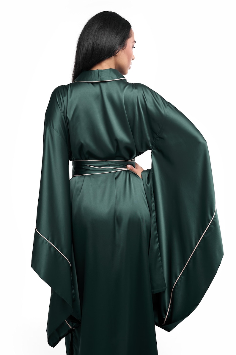 May include: A long, dark green satin robe with a white trim. The robe has a wide, flowing silhouette and long sleeves.