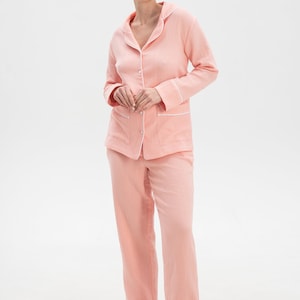 Peut inclure: Un ensemble pyjama rose avec des bordures blanches. Le haut a un devant boutonn&eacute; et des manches longues. Le pantalon a une jambe droite.