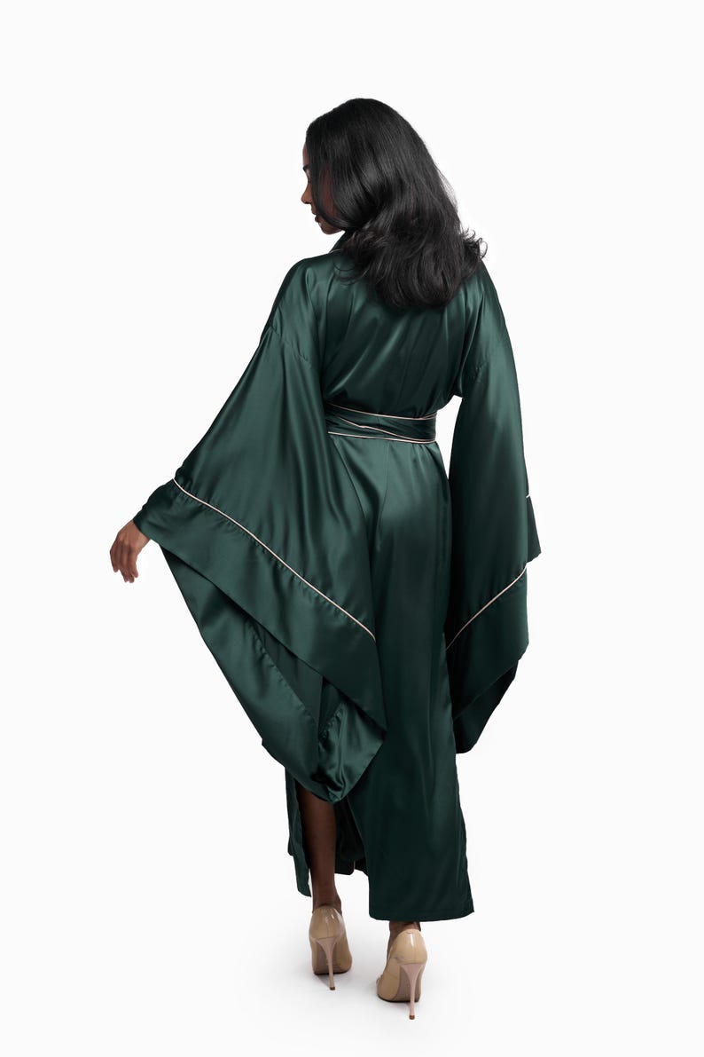 May include: A long, dark green satin robe with a white trim. The robe has wide sleeves and a sash that ties at the waist.